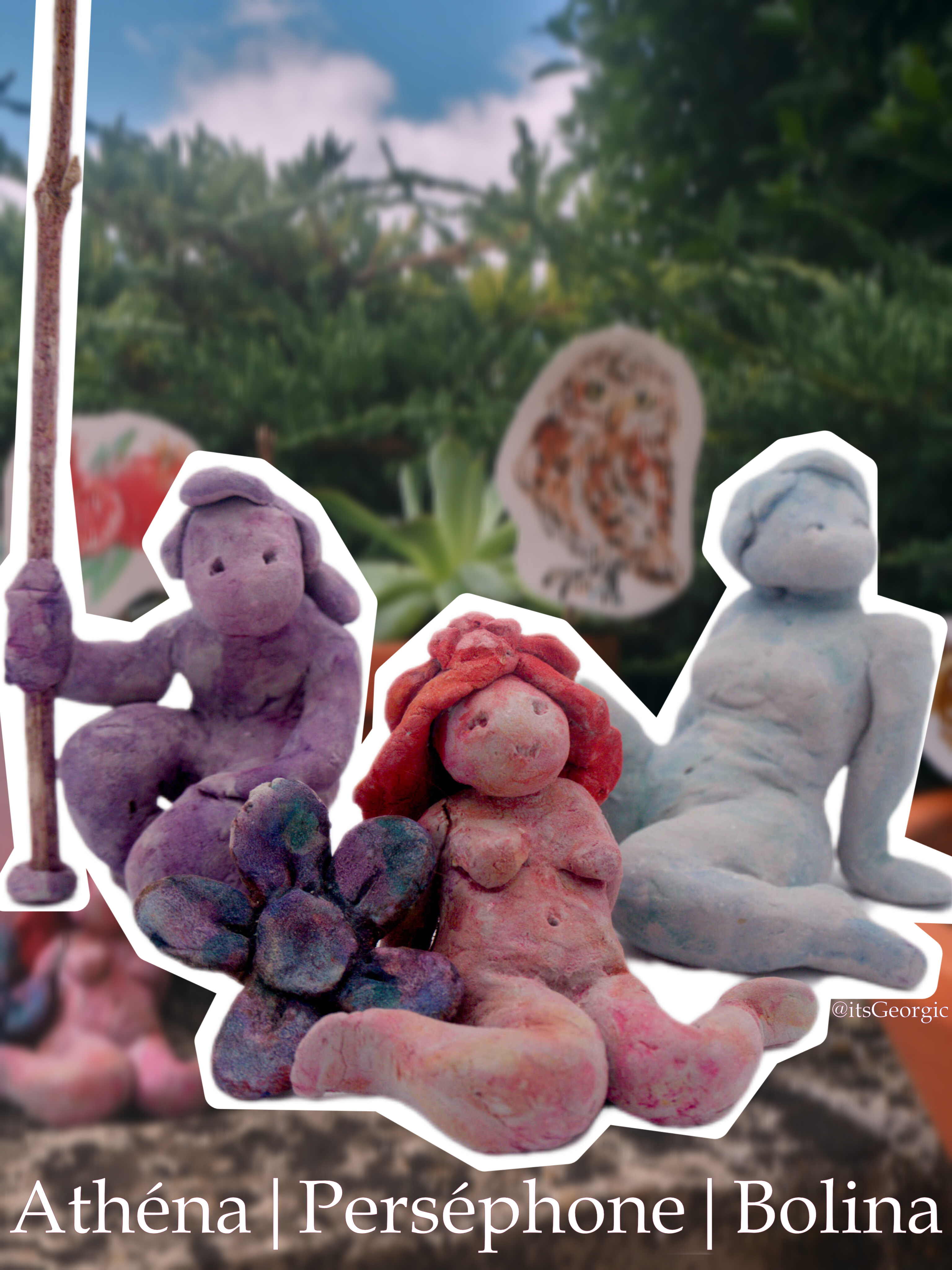 Trois statuettes, de gauche à droite : une statue violette d'une femme un genou à terre et une lance dans la main, une statue rose d'une femme assise en W avec une fleur violette, une statue bleue d'une femme installée sur le côté.