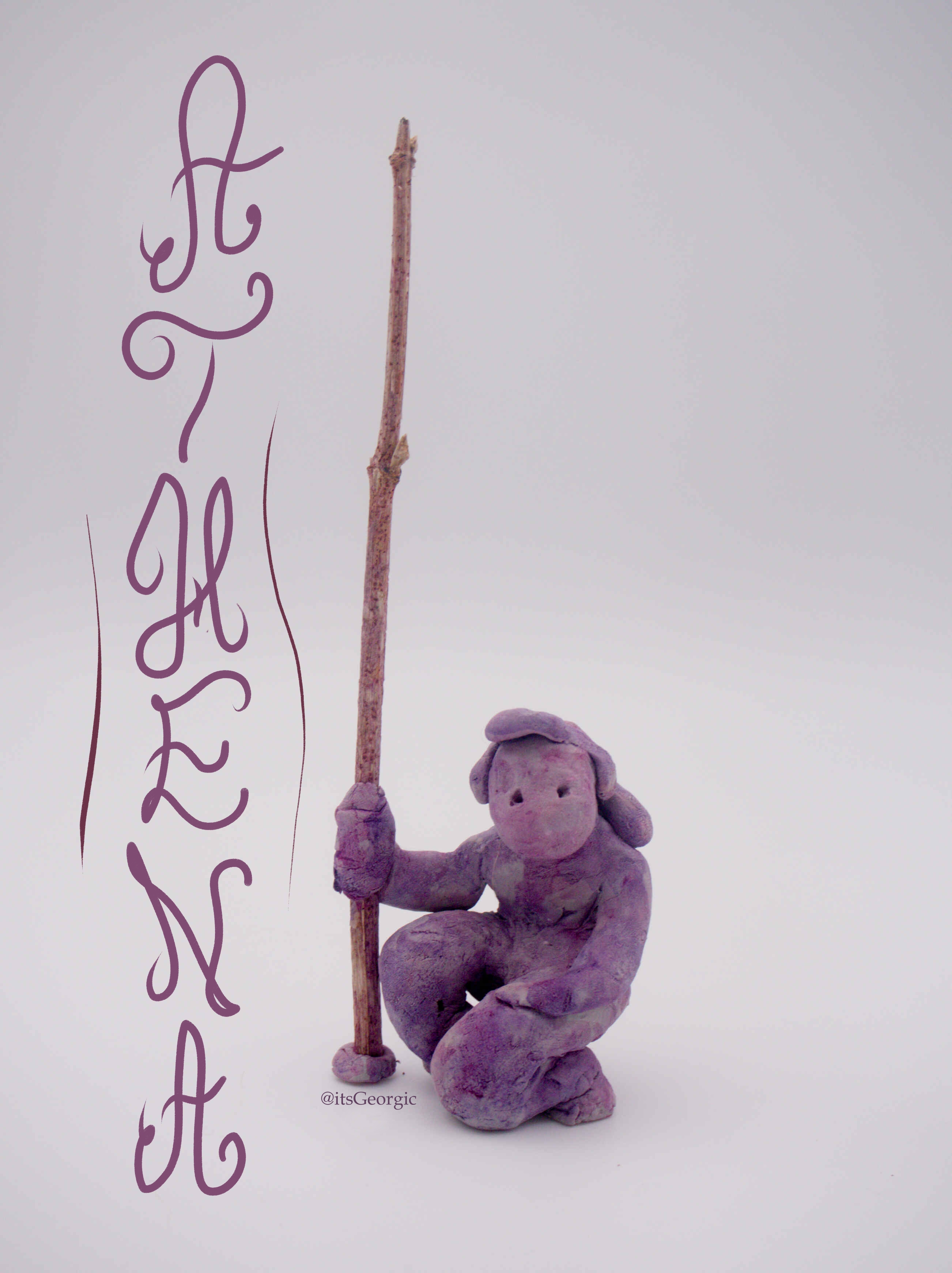 Photo d'une statuette féminine un genou à terre et une lance dans la main droite. Elle est peinte en violet avec un effet aquarelle.