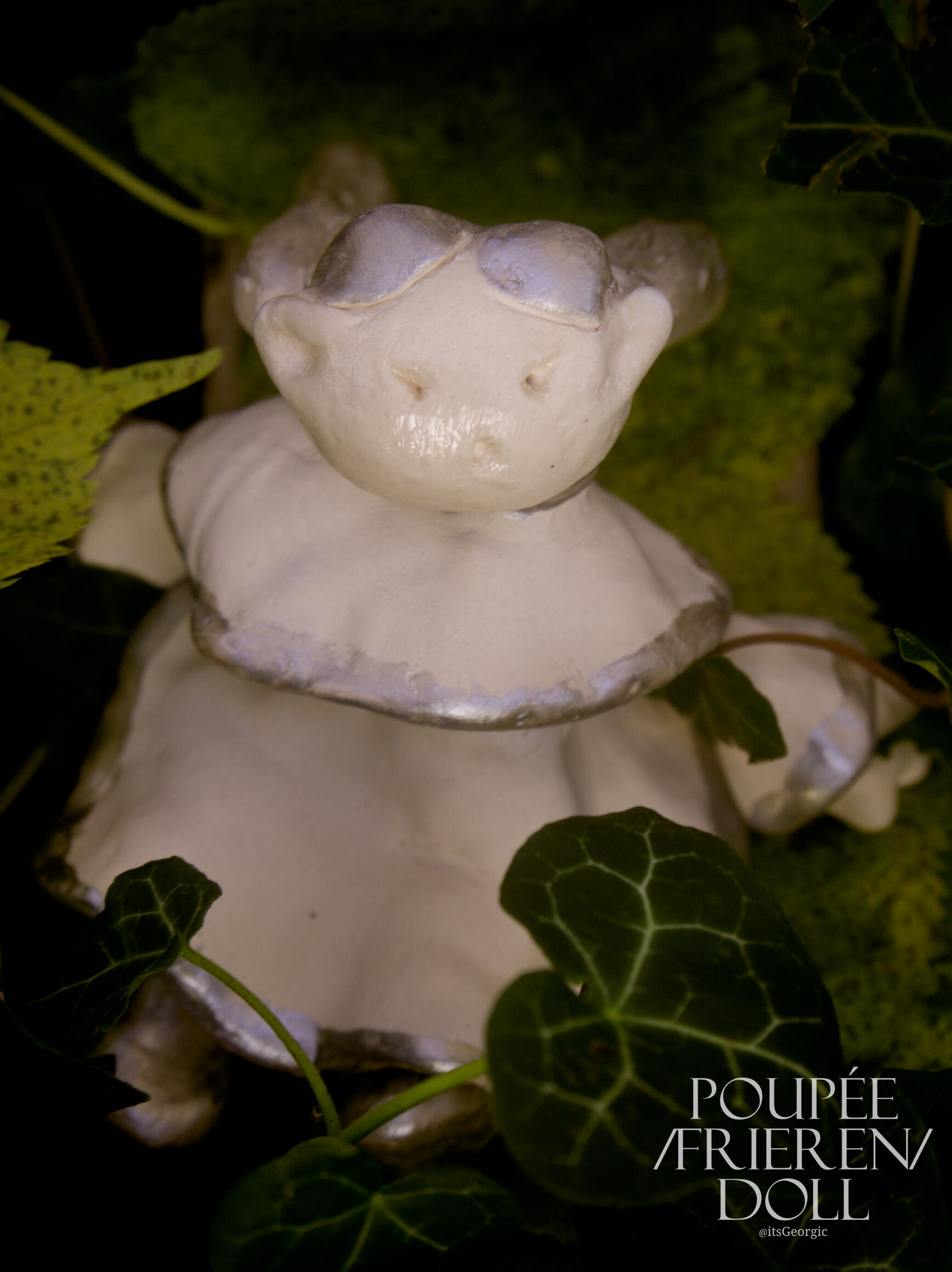 Photo de la poupée vue de dessus, elle est assise sur une feuille.