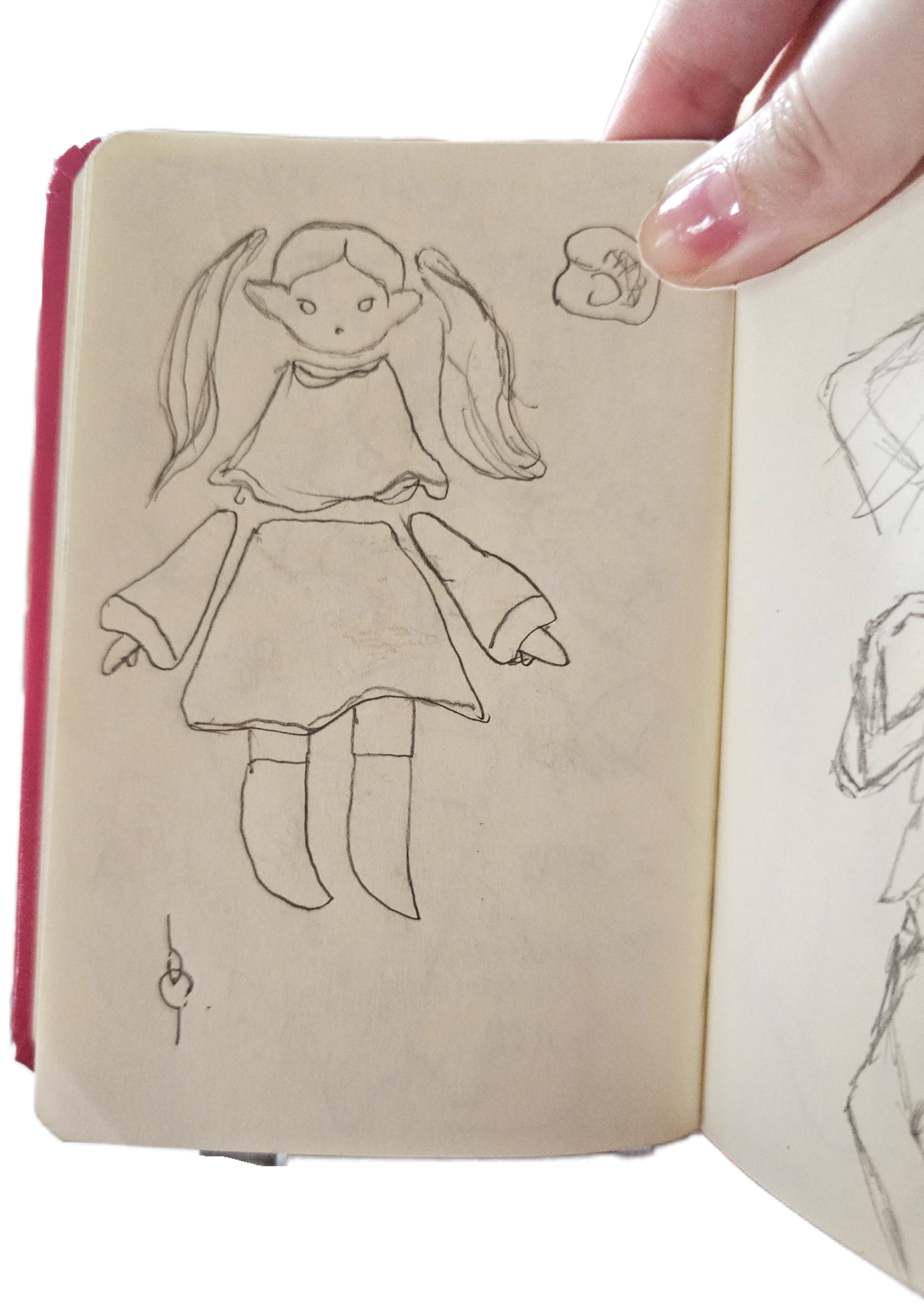 Photo d'un carnet de croquis où une poupée est dessinée, ses membres séparés.