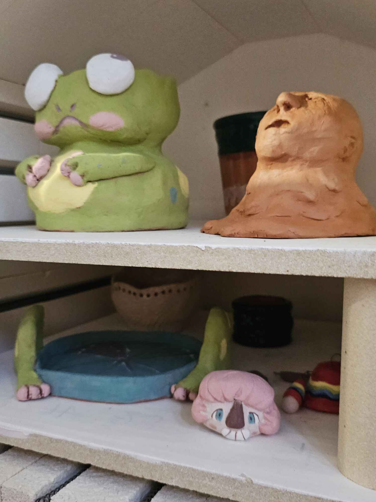 Photo d'un four de poterie avec une grenouille, une poupée et une tête fondante à l'intérieur